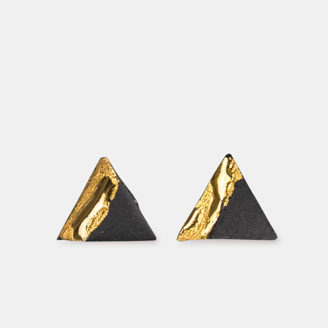 Pair of triangle-shaped earrings with black porcelain and gold by freakyfoxx on a light gray background