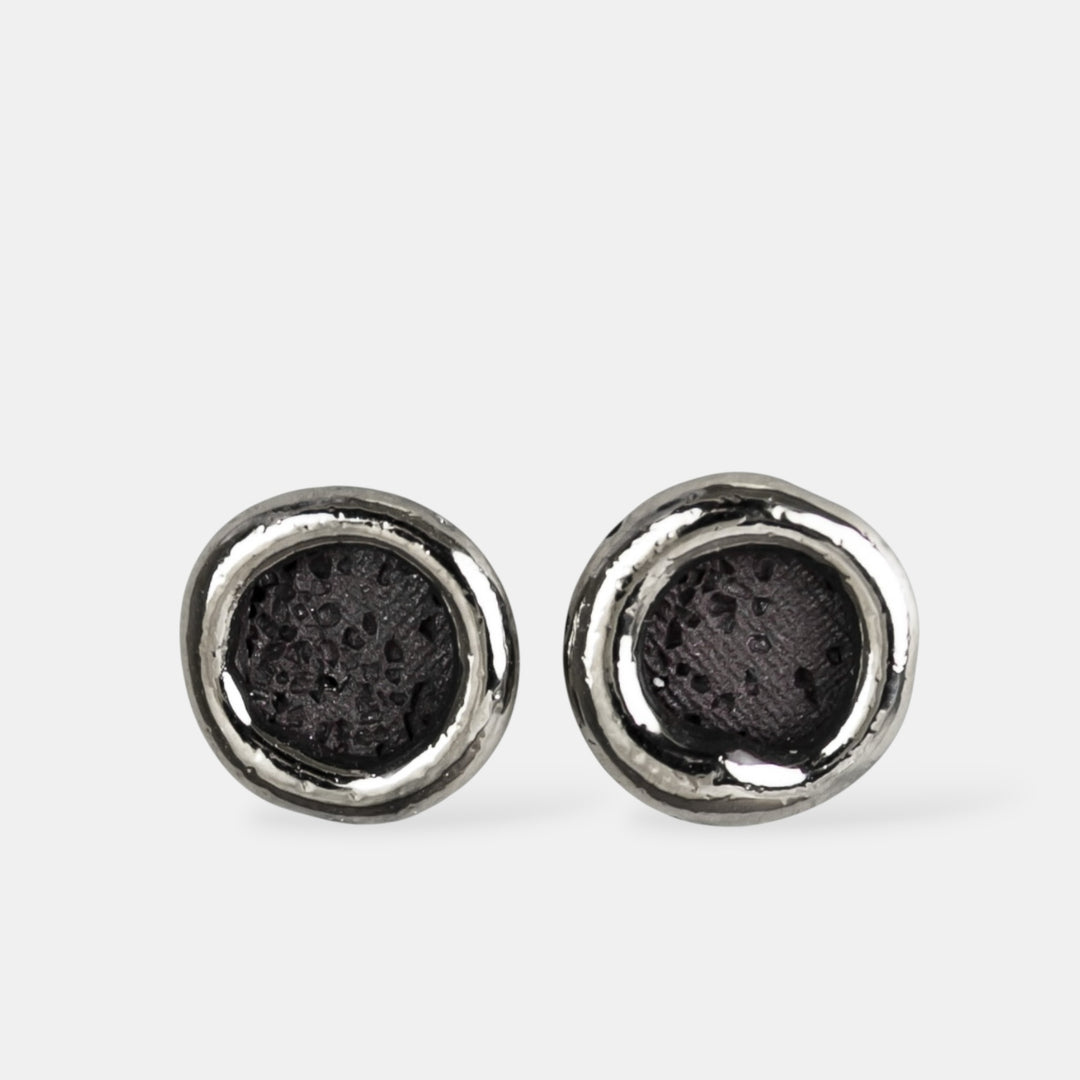 Pair of silver earrings with black centers on a white background
