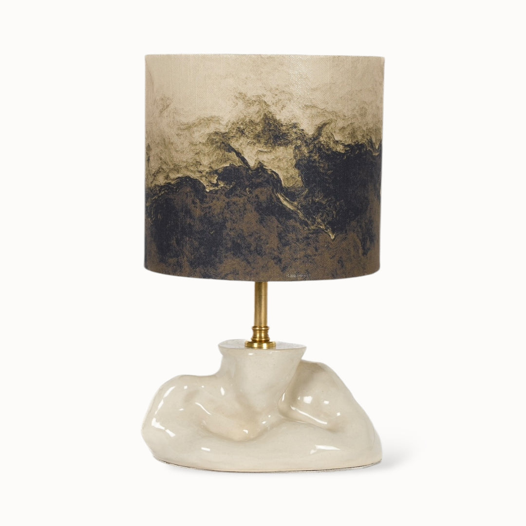 Handcrafted ceramic table lamp with a sculptural, fluid base and a linen blend lampshade featuring an abstract design.
Rankų darbo keraminis stalo šviestuvas su skulptūrišku, tekančios formos pagrindu ir lininio mišinio gaubtu su abstrakčiu dizainu.